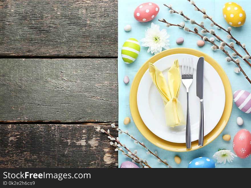 Kitchen cutlery with easter eggs and tree branches on grey wooden table