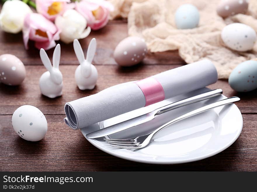 Kitchen cutlery with easter eggs and ceramic rabbits on wooden table