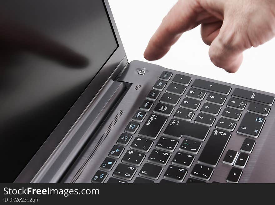 Silver laptop and moving man`s hand catching start button, on white background