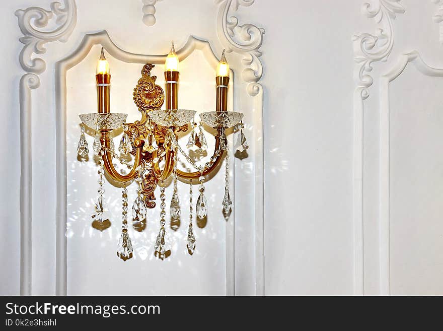 Vintage chandelier sconce lamp with candle lights on light wall, beautiful white wall light fixture