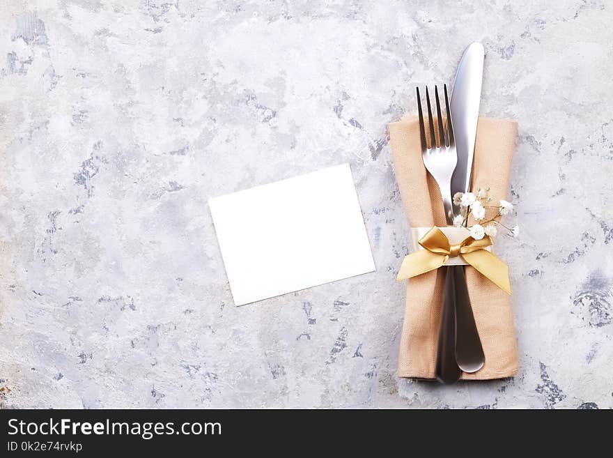 Easter table setting composition: fork, knife silverware wildflowers, willow on plate w/ napkin, white stucco plaster texture background. Close up, top view, copy space. Easter table setting composition: fork, knife silverware wildflowers, willow on plate w/ napkin, white stucco plaster texture background. Close up, top view, copy space