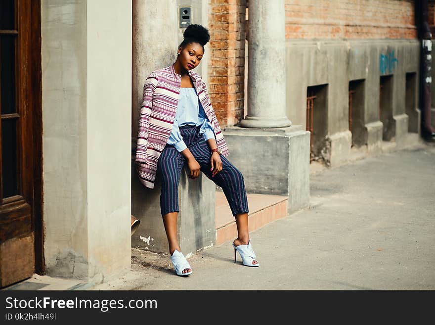 Woman Sitting on Gray Concrete Pillar