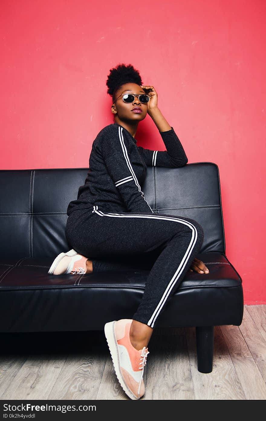 Woman Wearing Sunglasses Sits on Sofa Inside the Room