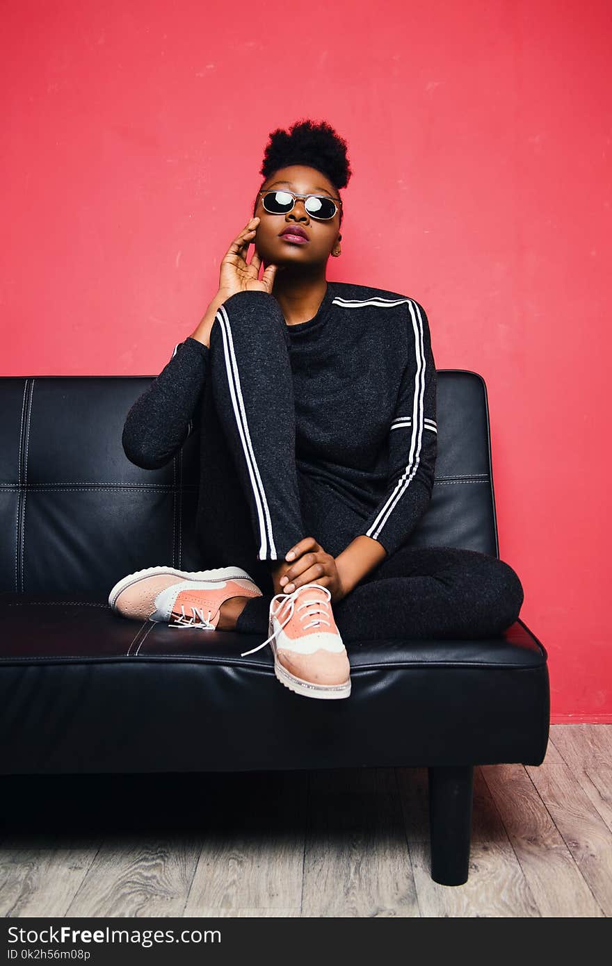 Woman Sitting on Sofa Bed Wearing Sunglasses