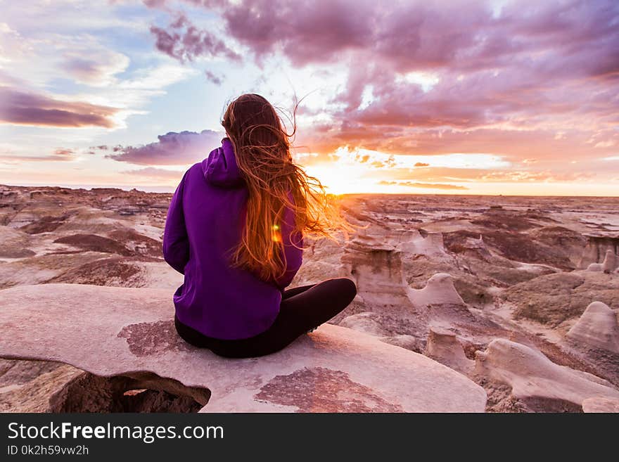 Woman Wearing Purple Hooded Jacket Sitting on Rock