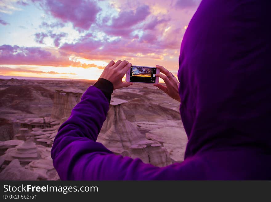 Person Wearing Purple Hoodie Jacket Holding Iphone 6 during Golden Hour