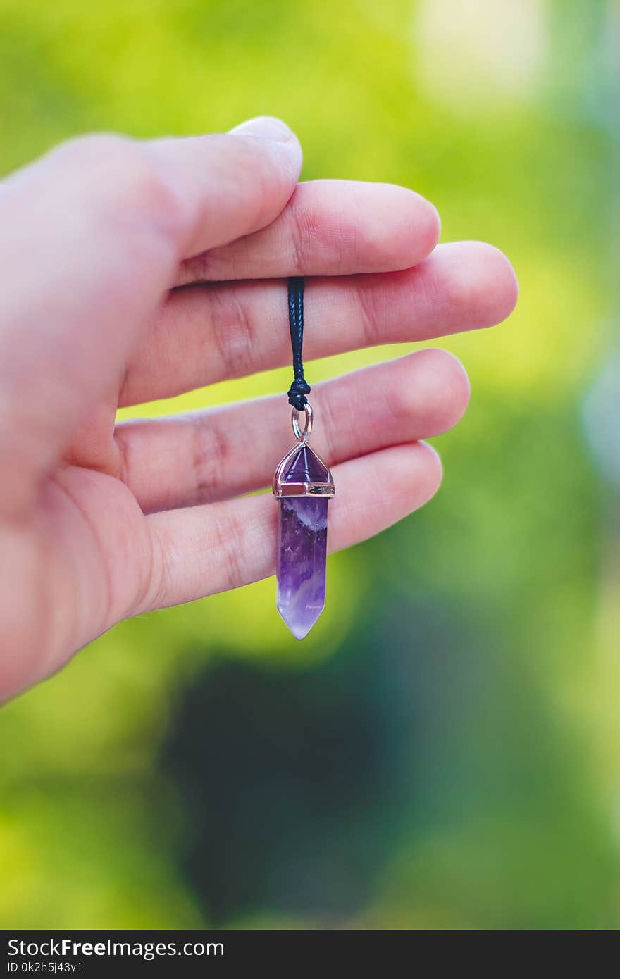 Person Holding Purple Gemstone Pendant