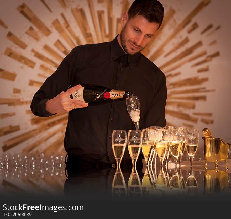 Man Wearing Black Dress Shirt Holding a Flute Glass and Black Wine Bottle