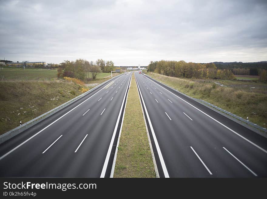 Two Grey Concrete Roads Between Green Grasses