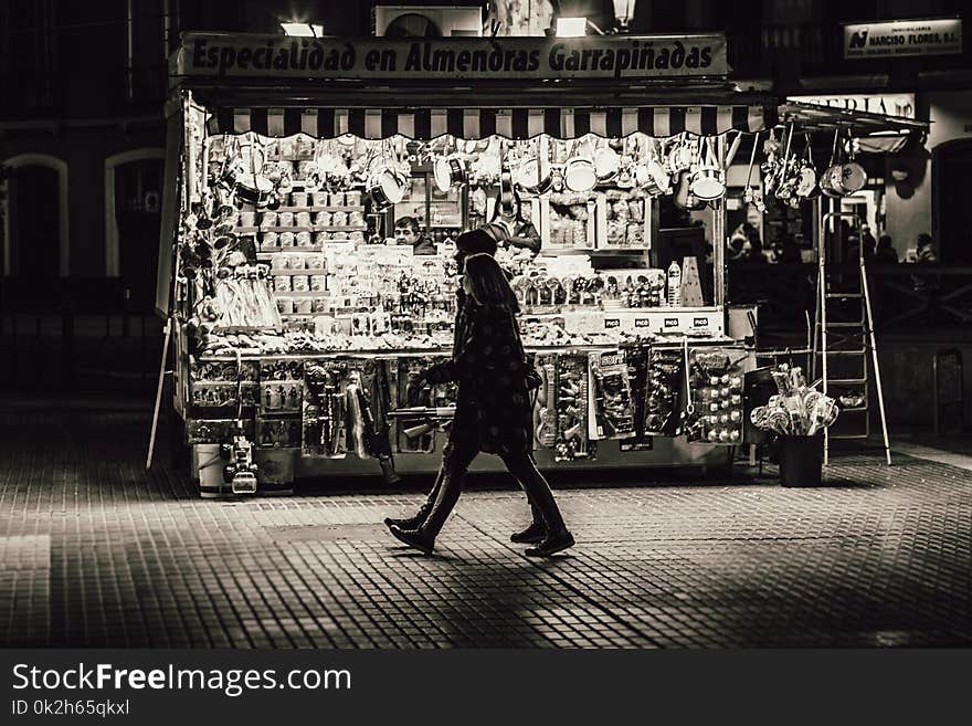 Man and Woman Walking in Front of Store Greyscale Photo