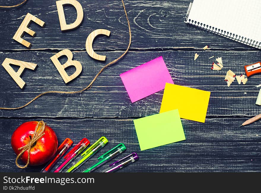 A student`s desk on a school board, a dark wooden background made of boards. Concept of education and school. Creative chaos. The office is on the table. Top view, space for text. Workplace.