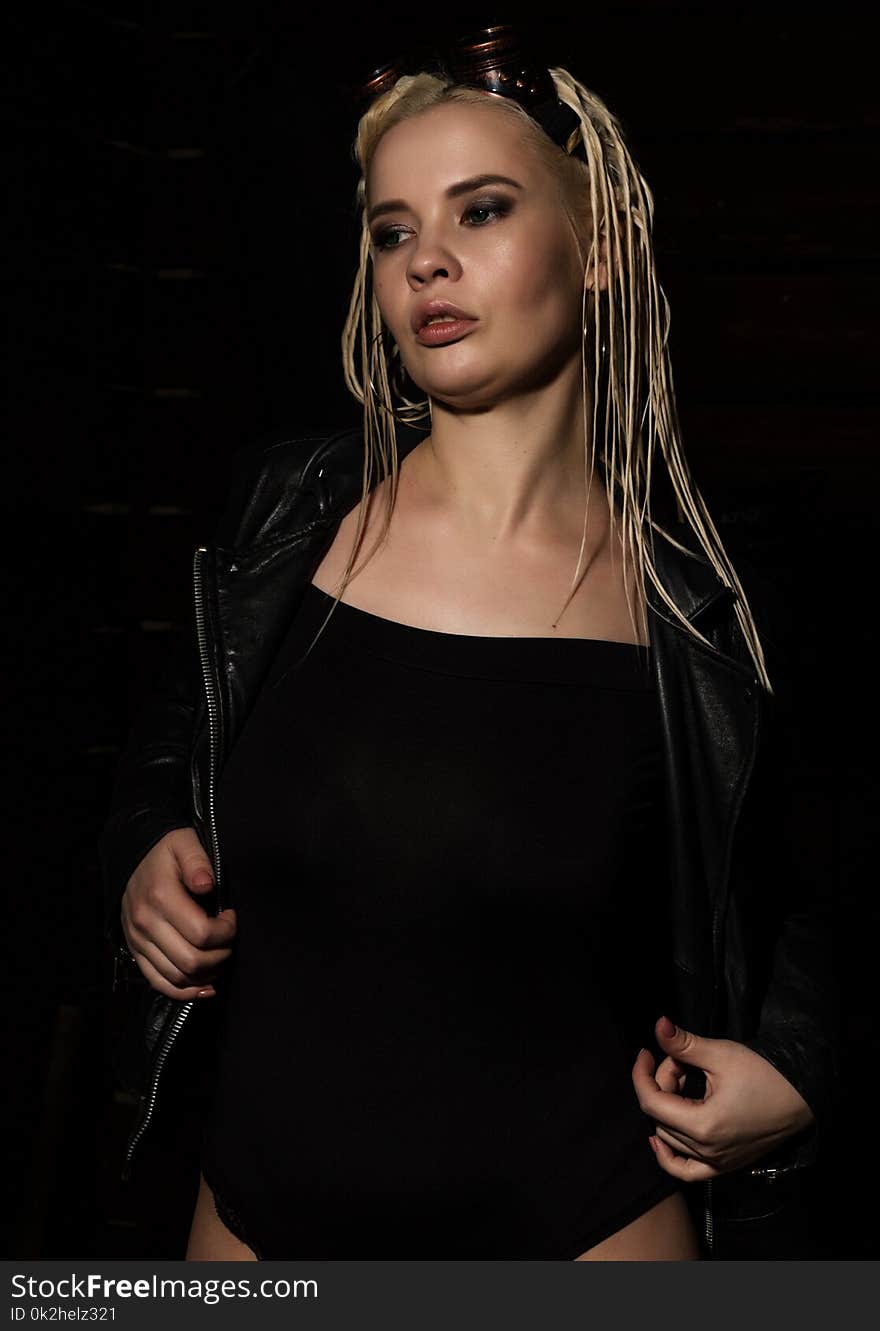 blonde beautiful woman with dreadlocks on a dark background in the studio