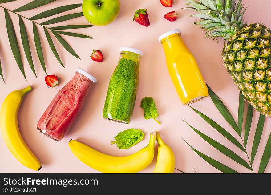 Flat-lay of colorful smoothies in bottles with fresh fruits and on pink background, top view. Natural Organic Food Style. Flat-lay of colorful smoothies in bottles with fresh fruits and on pink background, top view. Natural Organic Food Style.