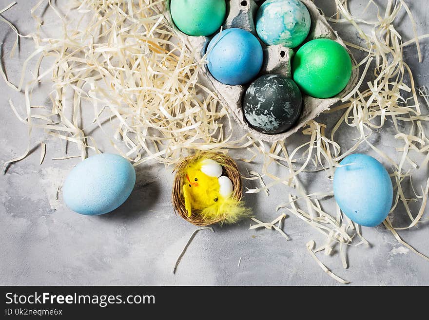 Painted eggs in tray, chicken eggs, paint and brush on concrete surface, Easter decorations. Top view