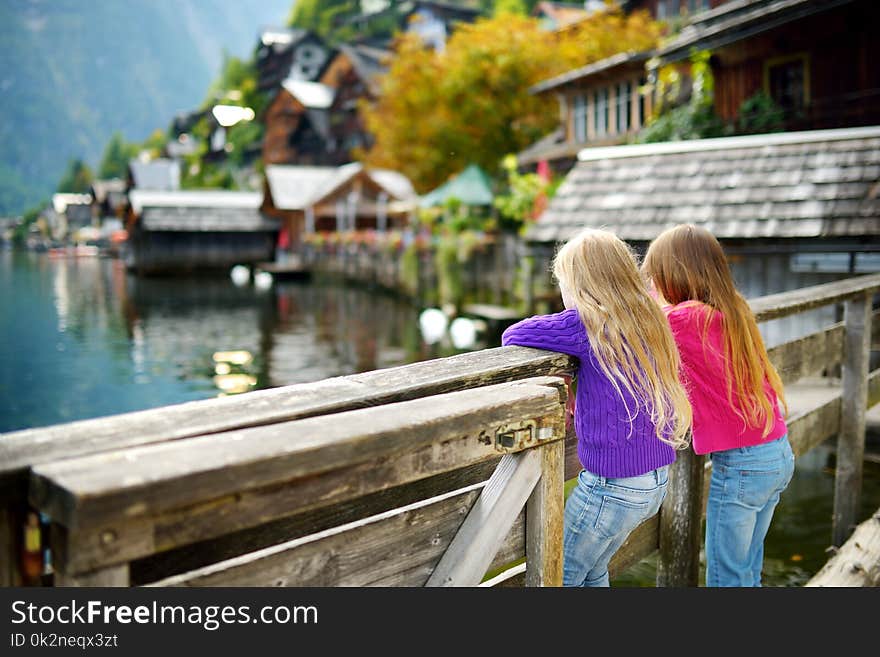 Two girls enjoying the scenic view of Hallstatt lakeside town in the Austrian Alps in beautiful evening light on beautiful day in