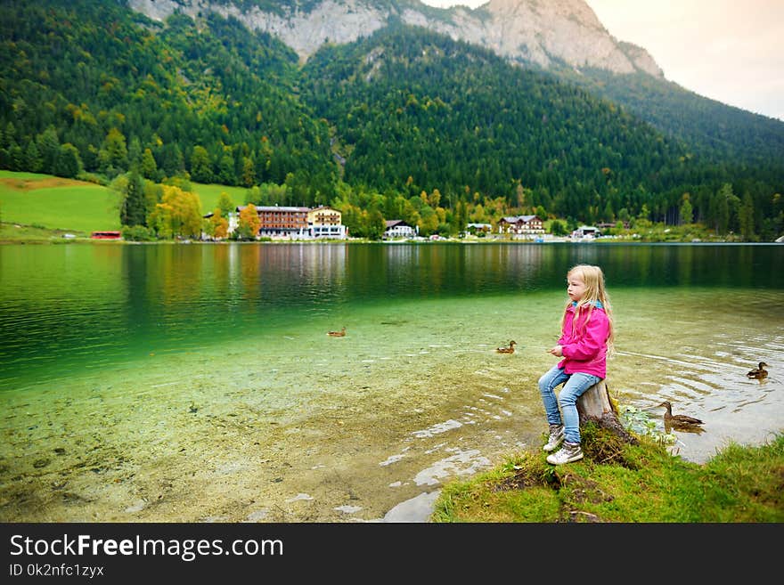 Cute little girl enjoying the view of wonderful green waters of Hintersee lake. Amazing autumn landscape of Bavarian Alps on the Austrian border, Germany, Europe.