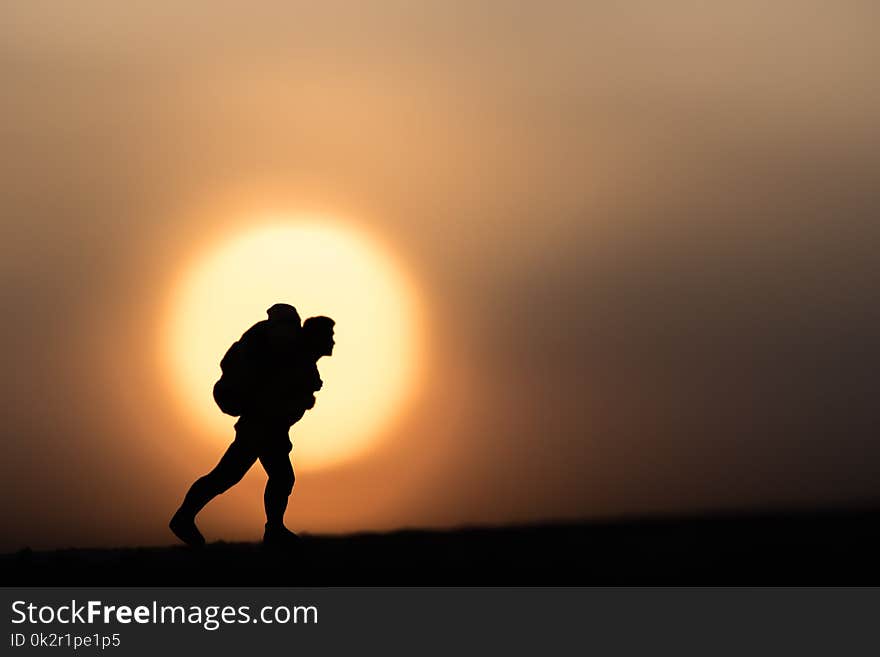 Silhouette traveler backpacker alone on a sunset background.