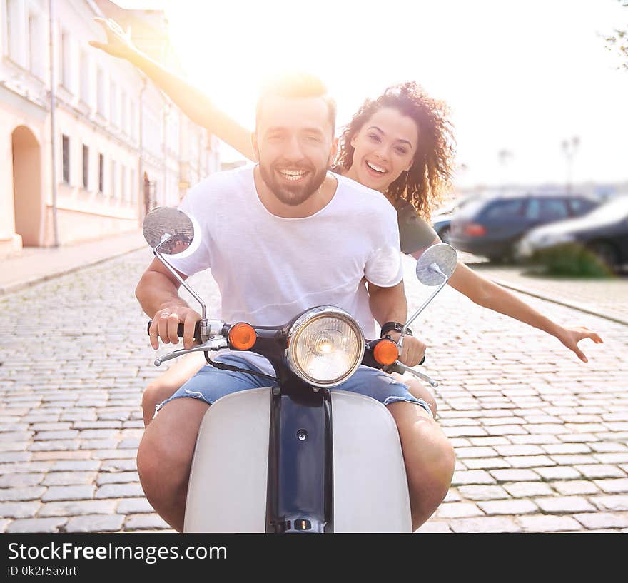 Cheerful young couple riding a scooter and having fun