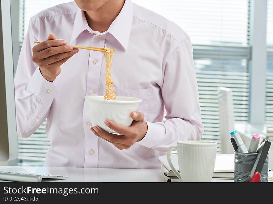 Cropped image of businessman eating instant noodles for lunch