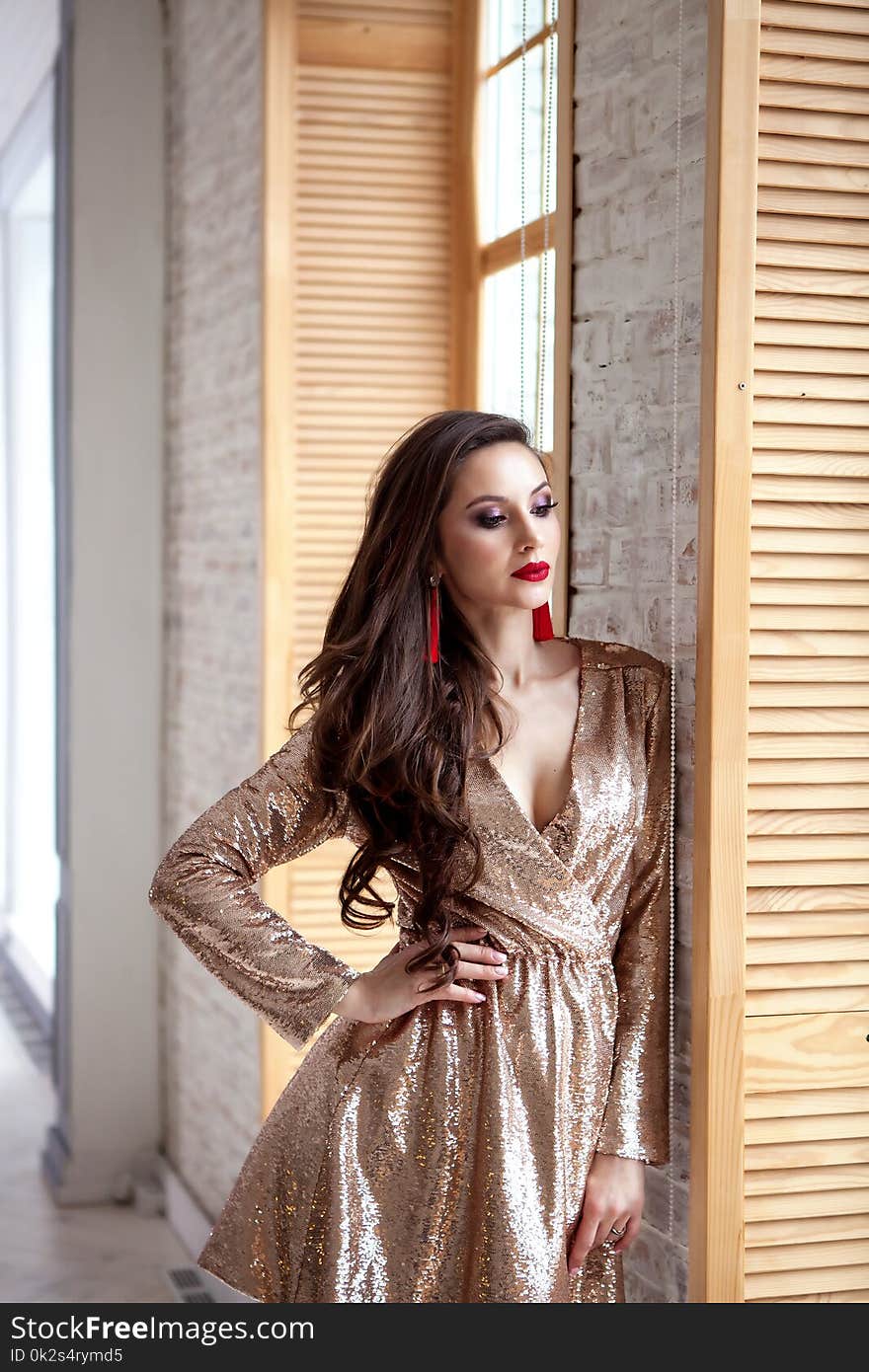 Amazing luxury woman in stylish gold shining party dress . Bright smokey eyes make up, red full lips, healthy wavy hairs