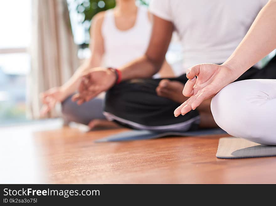 Cropped image of people meditating together in fitness club. Cropped image of people meditating together in fitness club