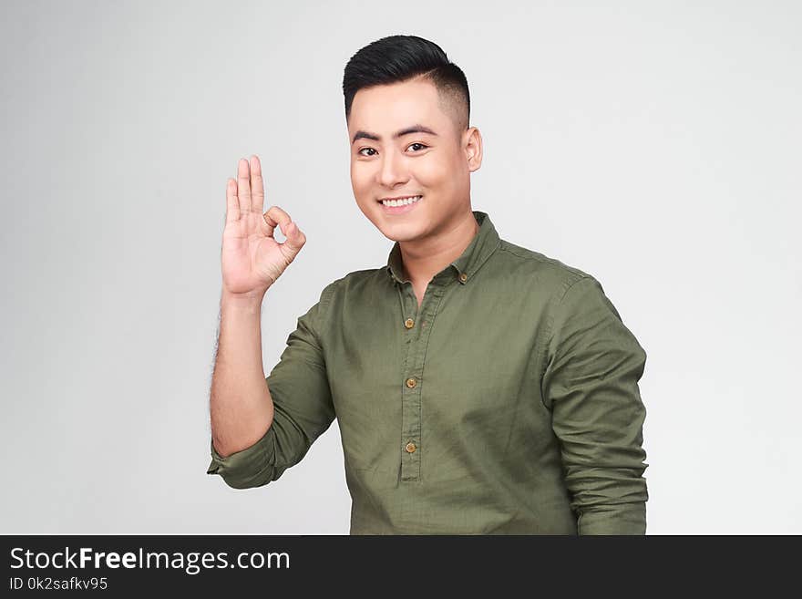 Portrait of a cheerful young asian man showing okay gesture