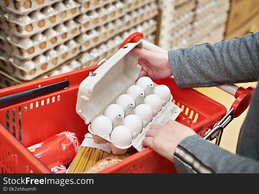 Hands with packages of white eggs in store