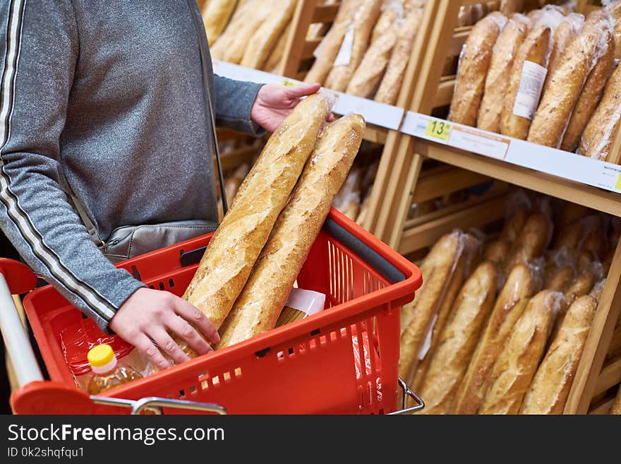 Buyer with bread baguettes with a grocery basket in the store. Buyer with bread baguettes with a grocery basket in the store