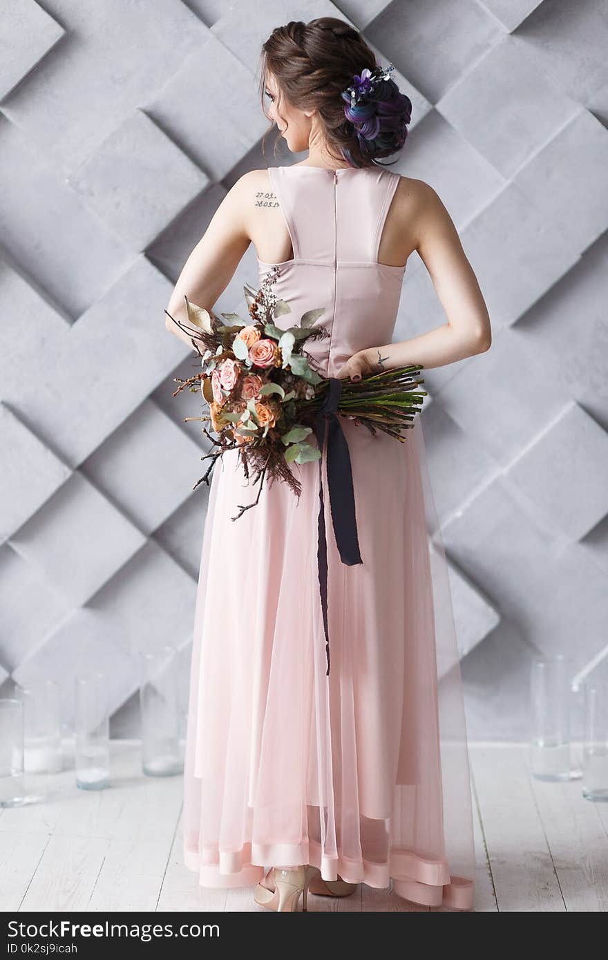 The Bride or Young woman in wedding dress standing back to camera holding bouquet.