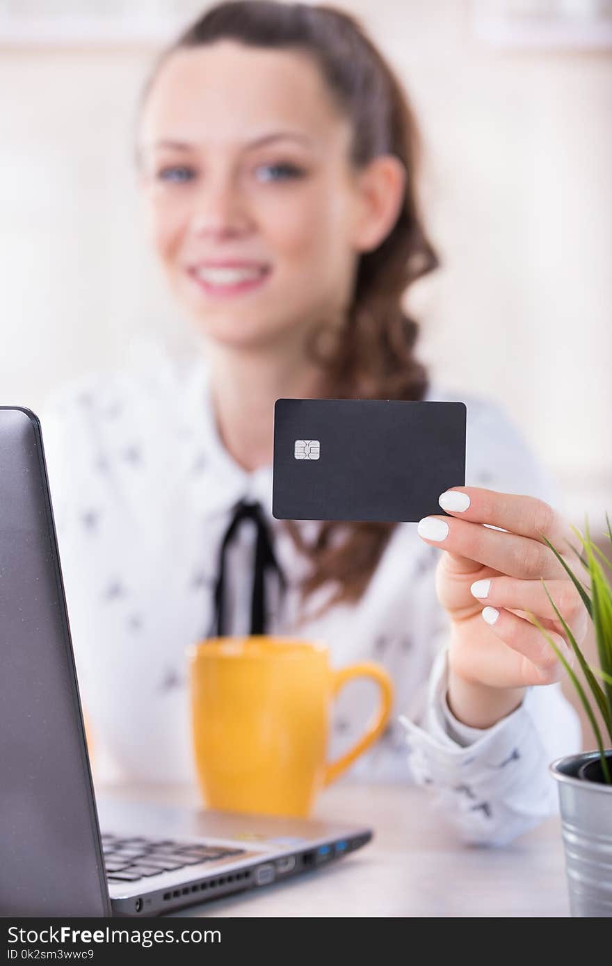 Close up of credit card in pretty young woman`s hand. Girl shopping online at table. E-business concept. Close up of credit card in pretty young woman`s hand. Girl shopping online at table. E-business concept