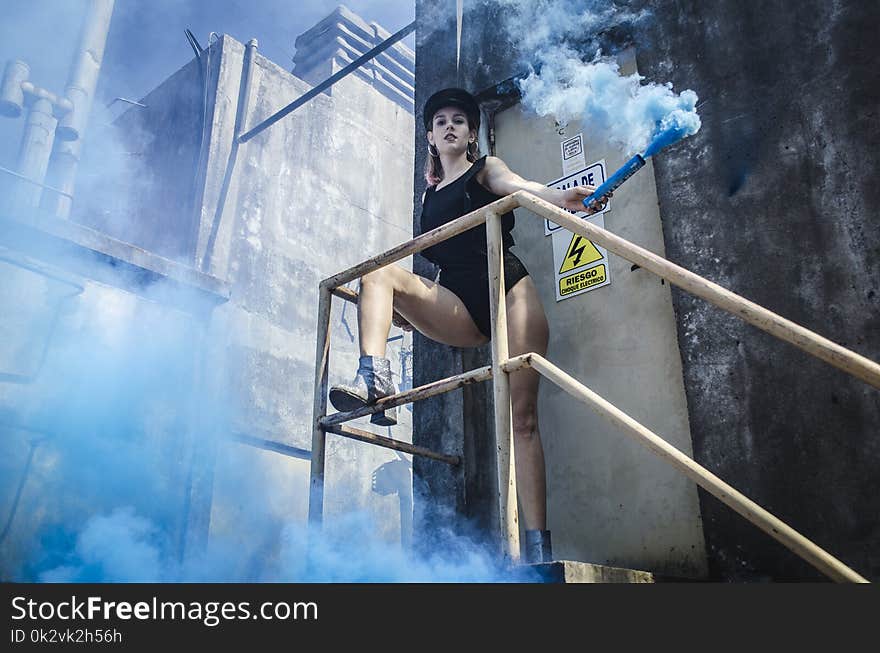 Woman in Black Onepiece Holding Smoke Bomb Near Close Door