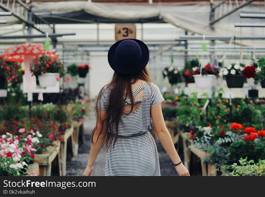 Woman Walking Between Display of Flowers and Plants