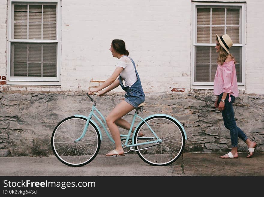 Woman Riding on Teal Cruiser Bike Near Woman Wearing Pink Long-sleeved Shirt