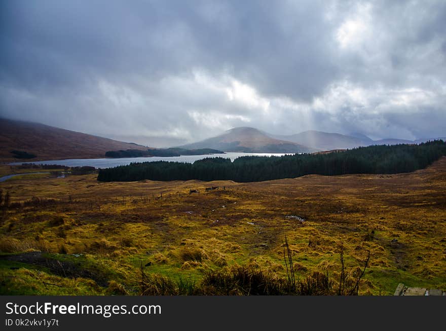 Mountain Beside Body of Water Under White Clouds