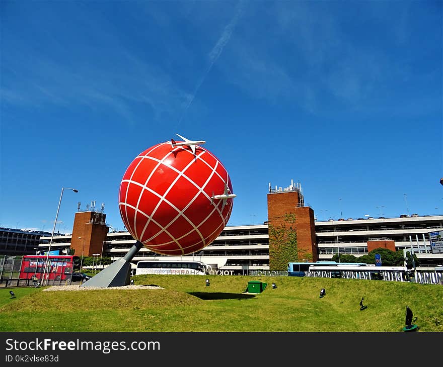 Red and White Globe Statue Near Brown and White Concrete Building