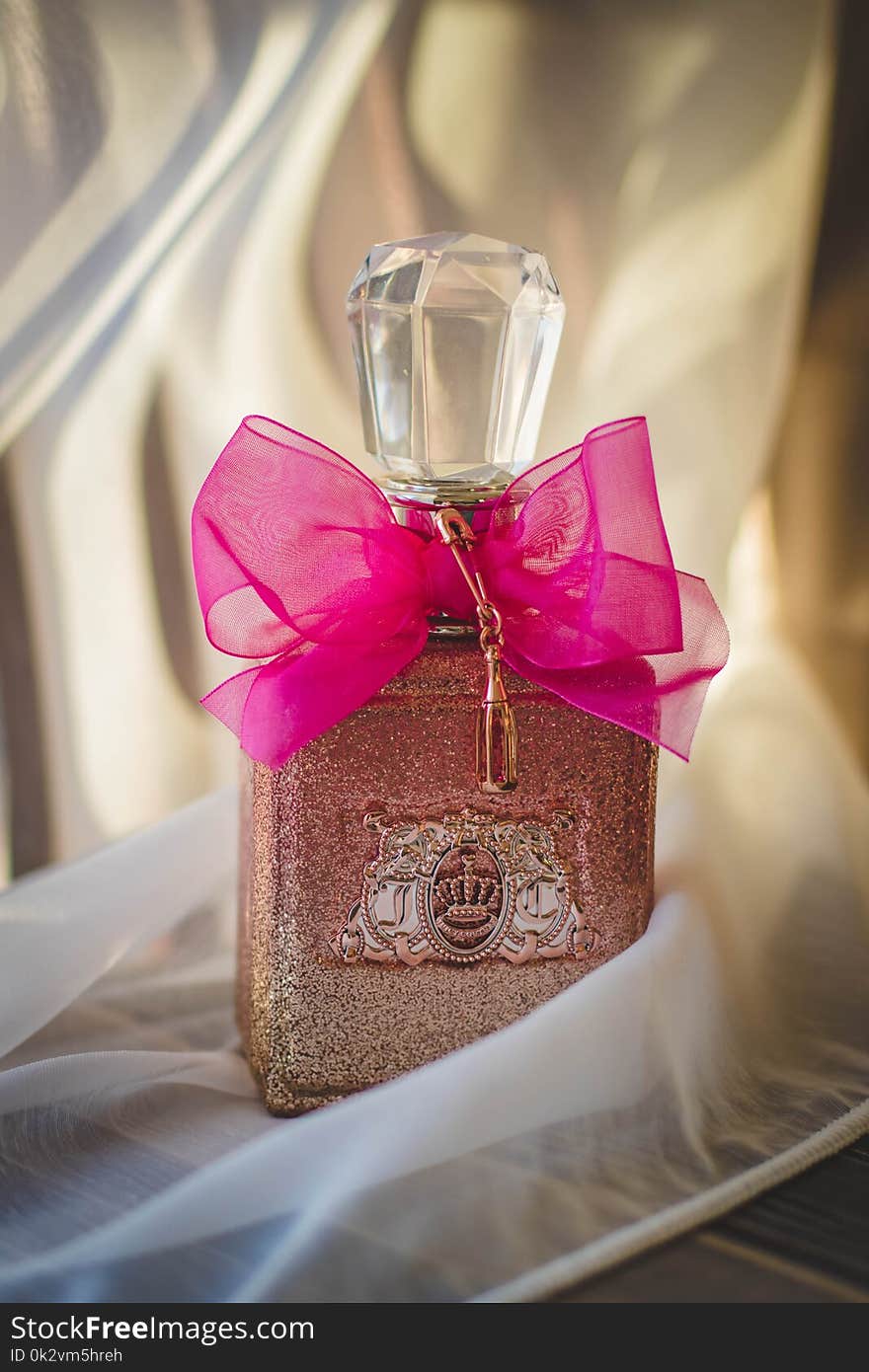 Close Photograph of Glitter Pink Fragrance Bottle With Red Ribbon