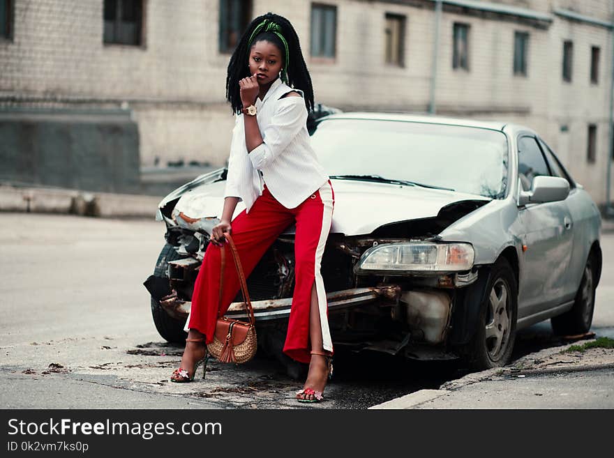 Woman With White Long-sleeved Shirt, Red ,and White Slit Pants and Pair of Black Open-toe D&#x27;orsay Heel Sandals Sitting on Wrecked Silver Car