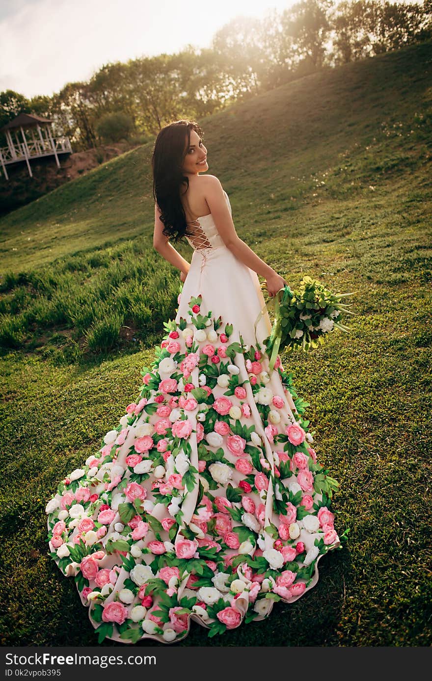 Young bride in a luxurious dress is walking on the grass and looking at the camera. Young bride in a luxurious dress is walking on the grass and looking at the camera