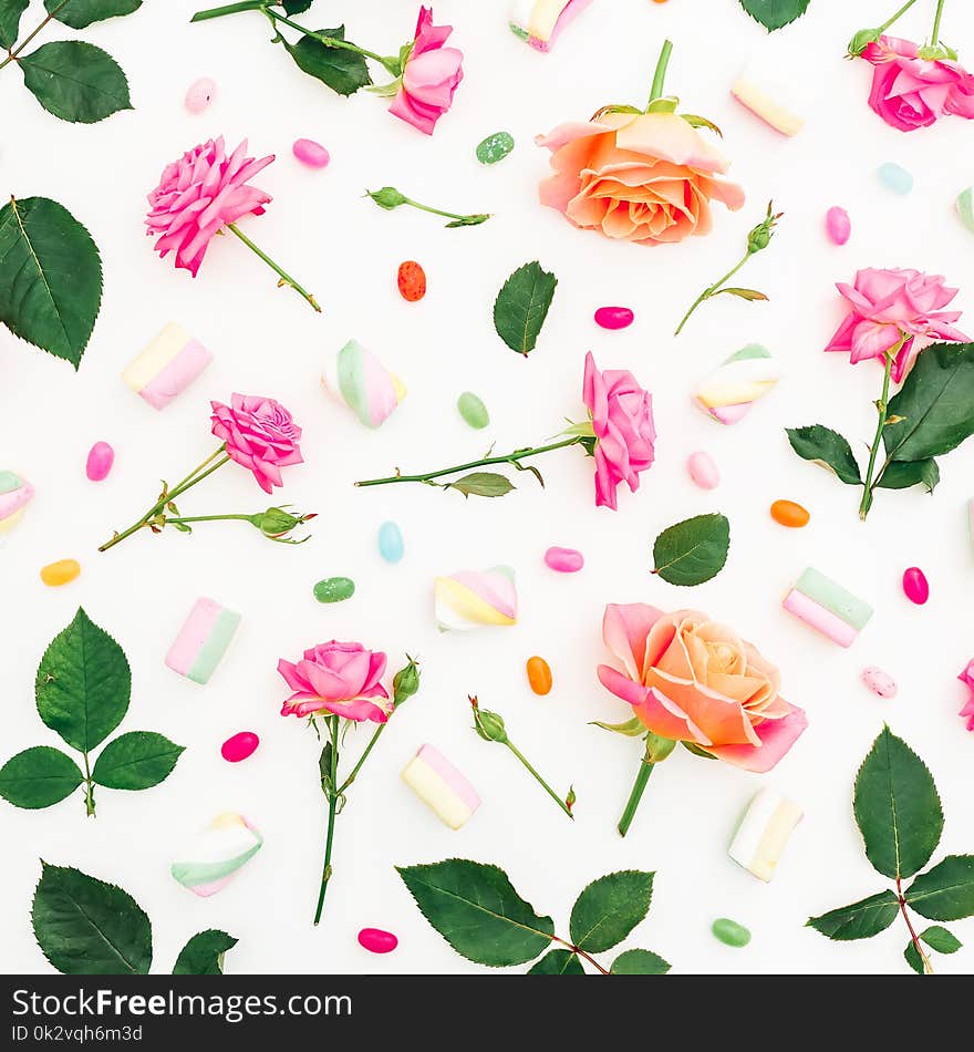 Pattern with roses, buds, leaves and marshmallow with candy on white background. Flat lay, top view. Spring background