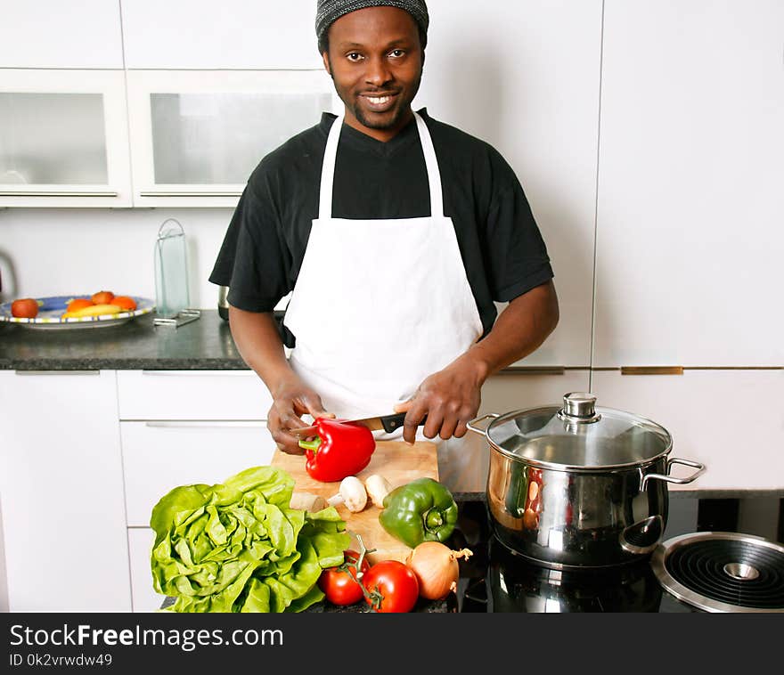 A young smiling, happy chef cooking in the kitchen with passion. A young smiling, happy chef cooking in the kitchen with passion