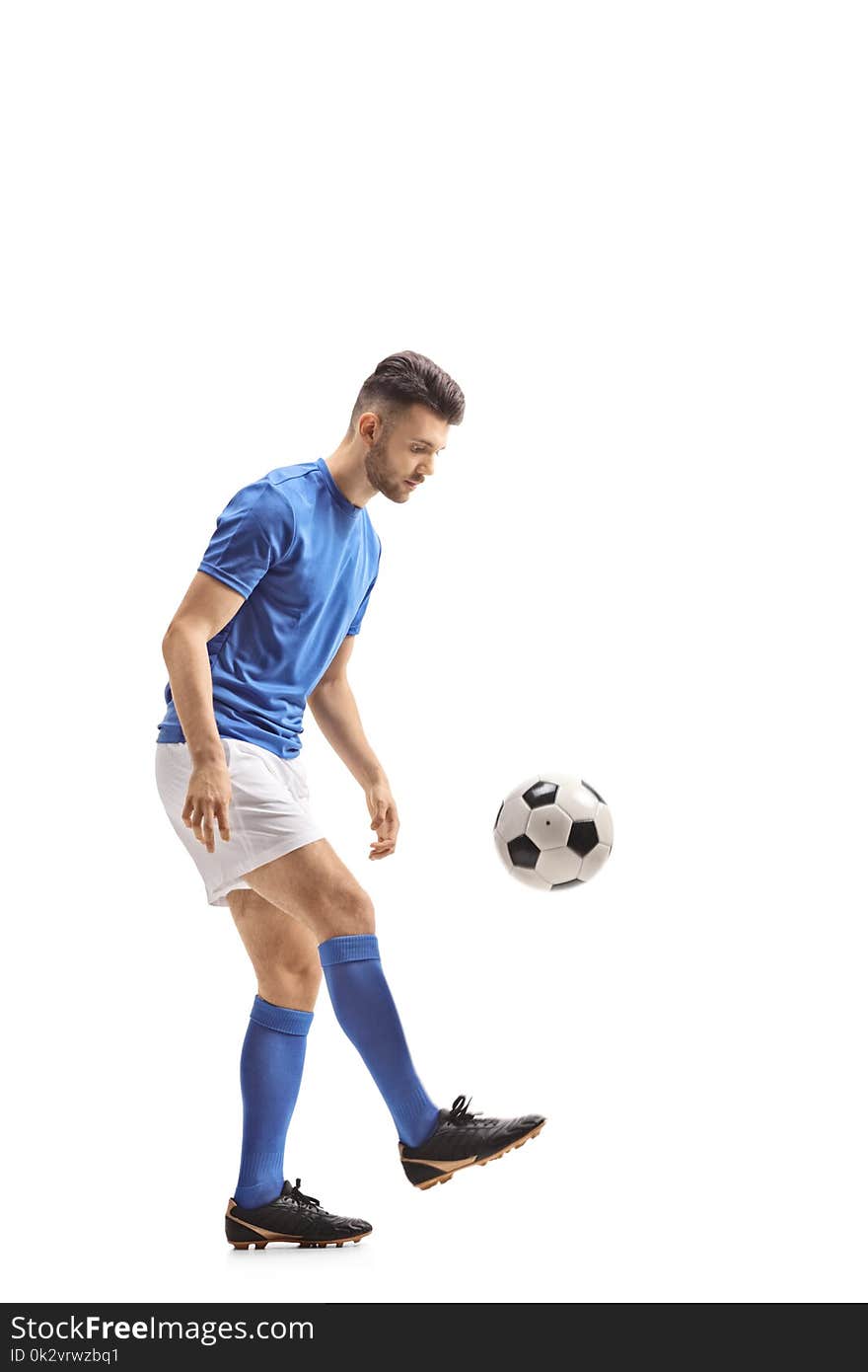 Full length profile shot of a soccer player with a football isolated on white background