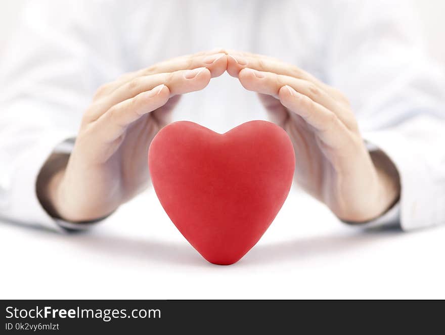 Red heart covered by hands. Health insurance or love concept