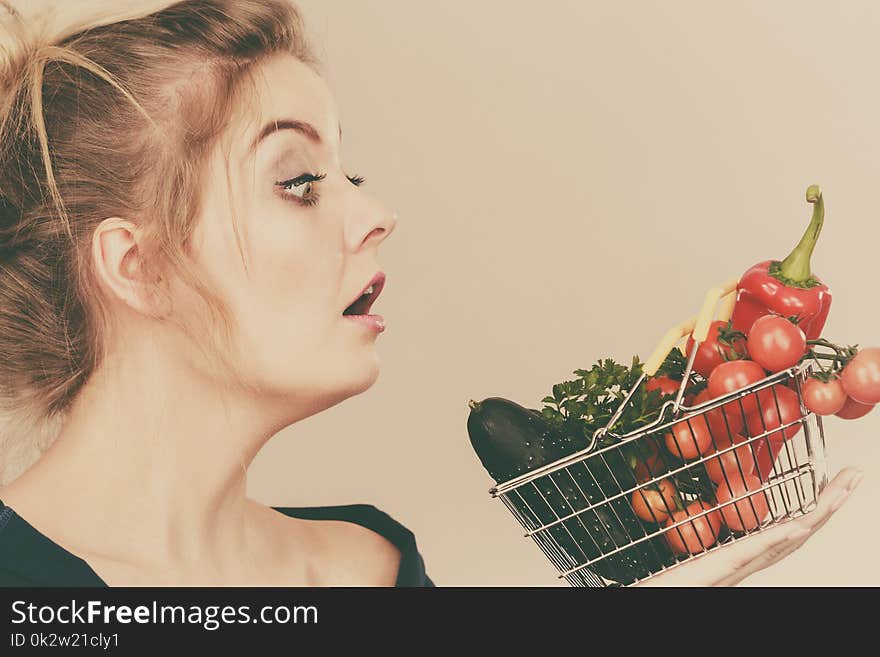 Adult woman do not like to eat raw food, questioning healthy lifestyle recommendations, origin vegetagles. Female holding small shopping basket with products, displeased shocked face expression. Adult woman do not like to eat raw food, questioning healthy lifestyle recommendations, origin vegetagles. Female holding small shopping basket with products, displeased shocked face expression