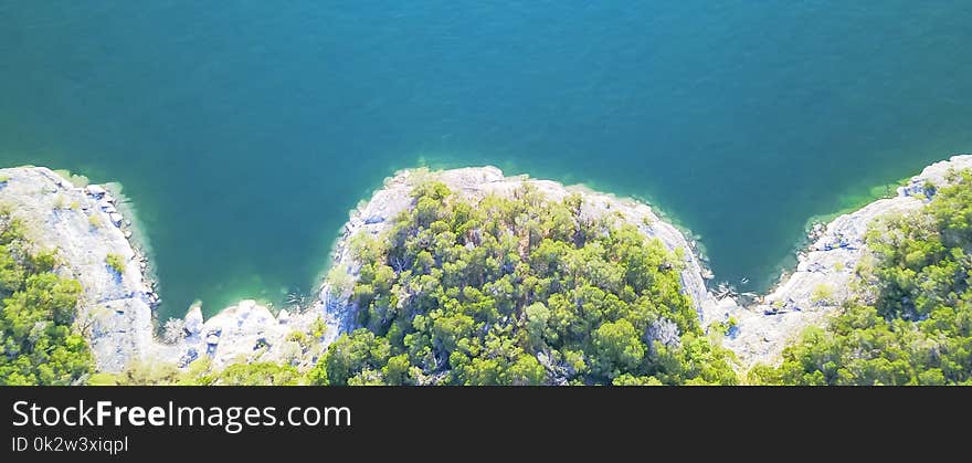 Panorama aerial view bluffs at Lake Travis, Austin, Texas, USA. Trees and cliff rock wall coming out of water from above. Blue ocean crystal, moderate waves looking straight down, green forest. Panorama aerial view bluffs at Lake Travis, Austin, Texas, USA. Trees and cliff rock wall coming out of water from above. Blue ocean crystal, moderate waves looking straight down, green forest