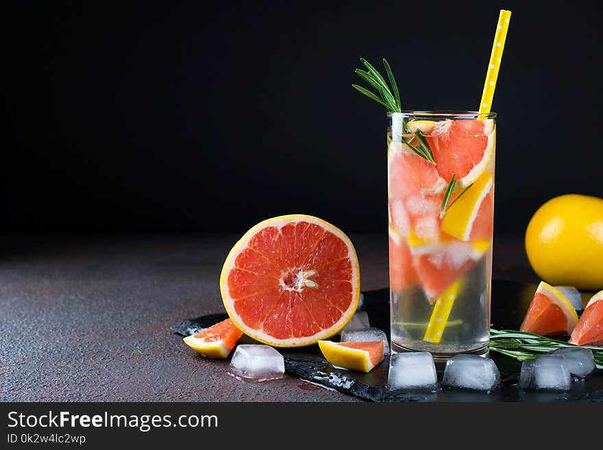 Grapefruit lemonade. Two glasses of refreshing drink, water with grapefruit, rosemary branches and ice. Recipe concept, cocktail