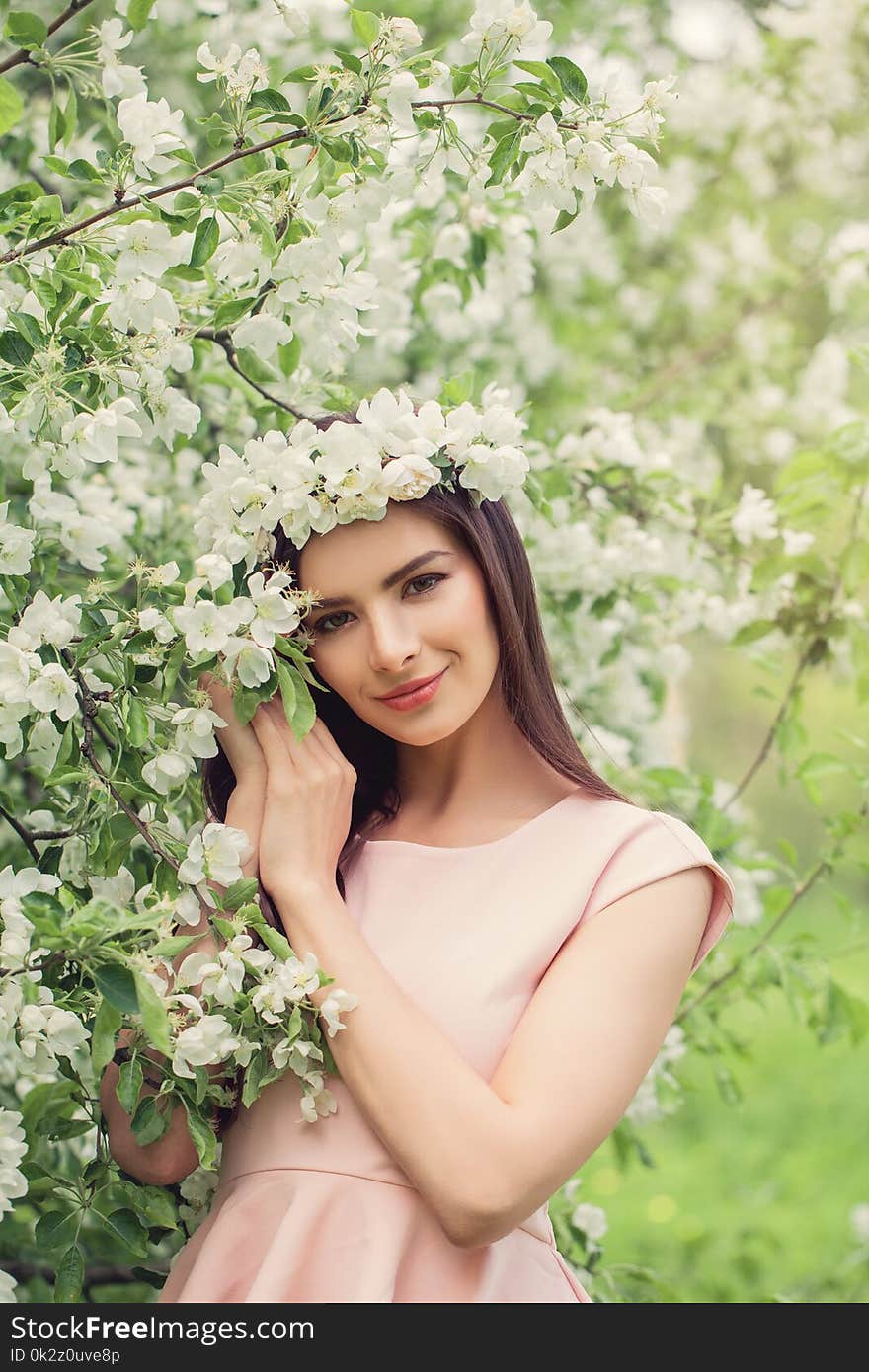 Spring woman outdoors on flowers background. Pretty young female model resting in blossom spring flowers garden