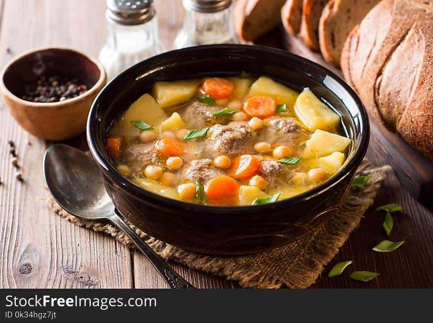 Soup with meatballs, vegetables and chickpea on wooden table. Selective focus.