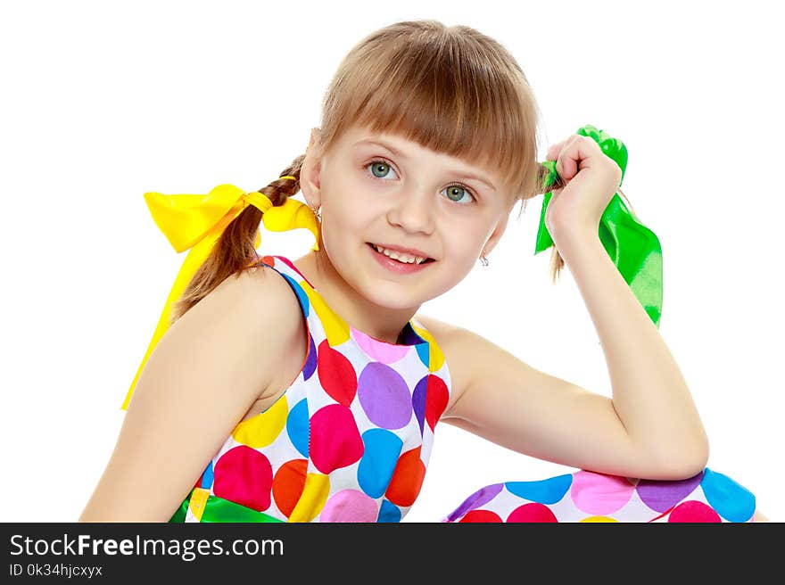 A little girl in a dress with a pattern from multi-colored circl