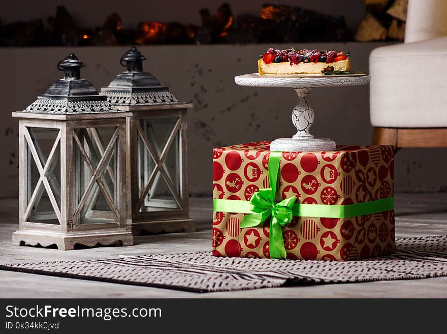 Delicious cheesecake section with different berry on the present box with gray lanterns on the floor. Delicious cheesecake section with different berry on the present box with gray lanterns on the floor