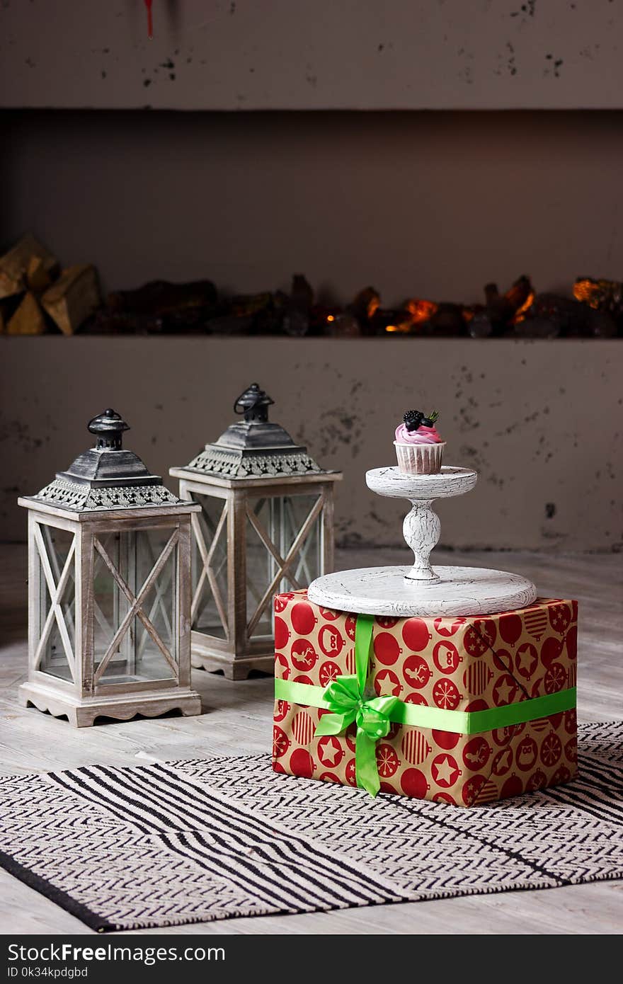 Delicious cupcake with berry on the present box with gray lanterns on the floor. Delicious cupcake with berry on the present box with gray lanterns on the floor